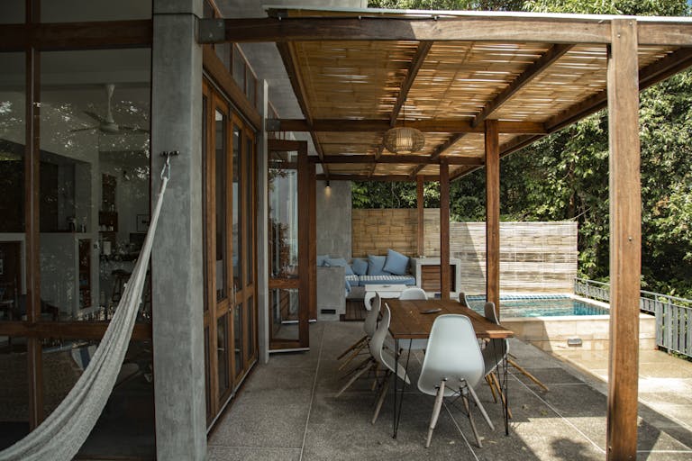 A stylish outdoor patio with wooden pergola and swimming pool, perfect for relaxation.