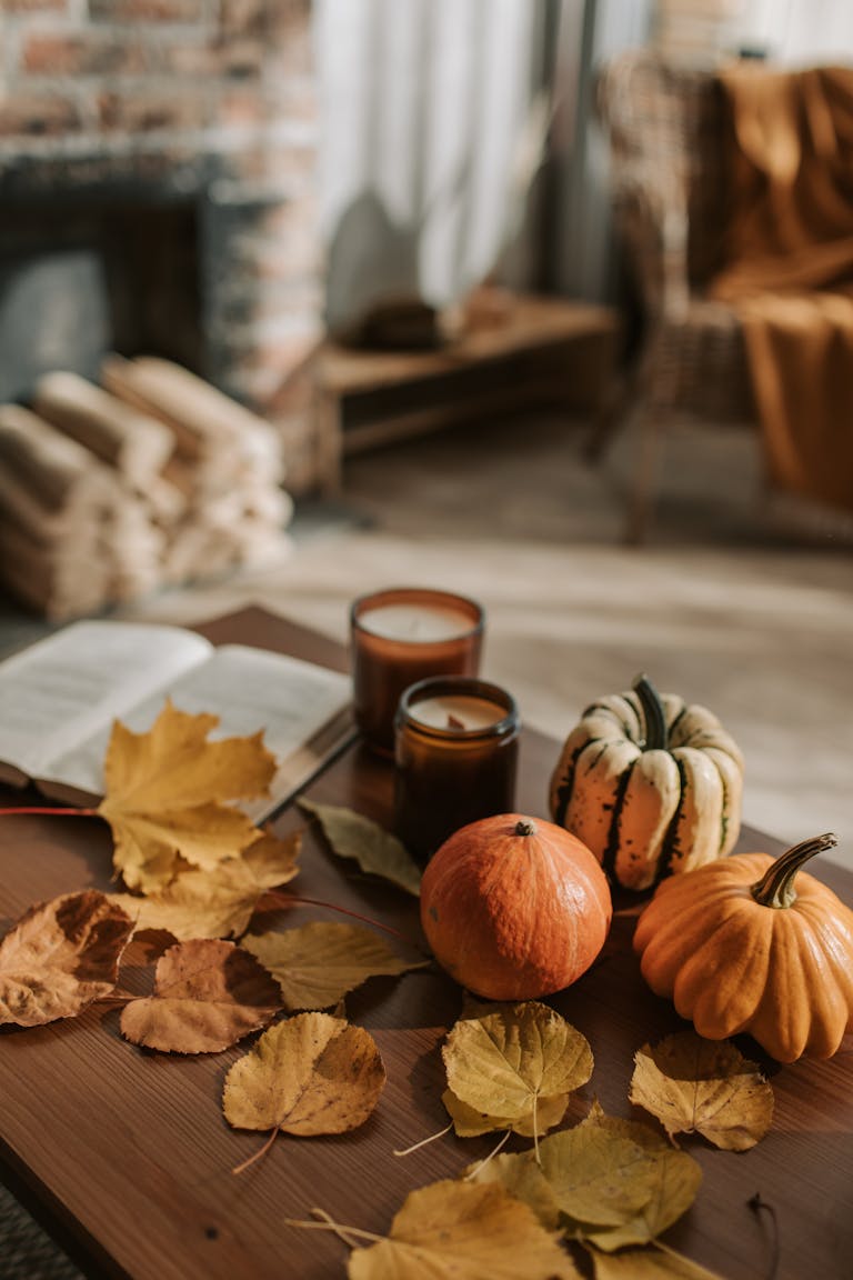 Warm indoor autumn scene with pumpkins and leaves on a wooden table.